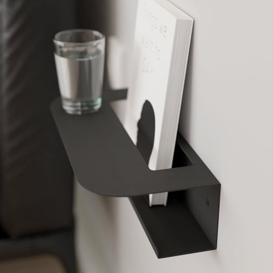 Modern black metal wall shelf holding a glass of water and a book, perfect for minimalist home decor by DnzHomeDesign.